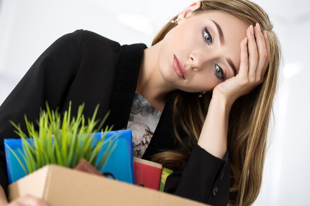 Jeune travailleuse licenciée au bureau tenant une boîte en carton avec ses effets personnels. Être viré concept.