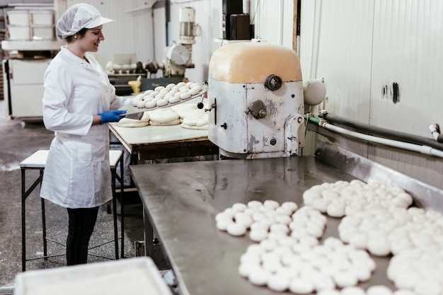 Jeune travailleuse travaillant dans une grande boulangerie. Préparation du pain.
