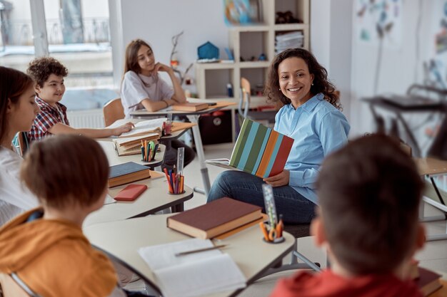 La jeune tutrice apprend à lire à son élève. Enfants de l'école élémentaire assis sur un bureau et lire des livres en classe.