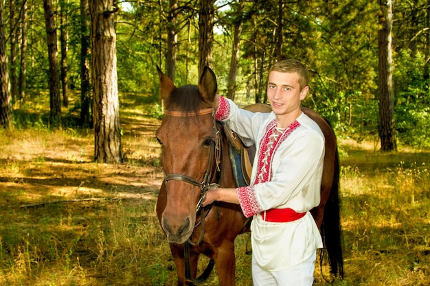 Jeune Ukrainien avec un cheval dans la forêt