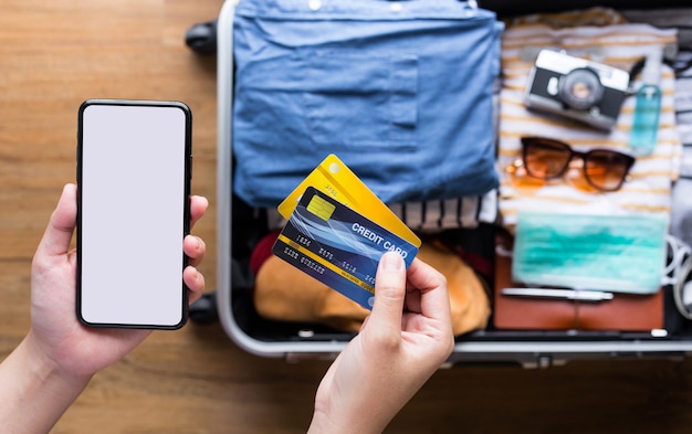 Jeune utilisant des cartes de crédit avec smartphone pour le paiement du billet ou la réservation