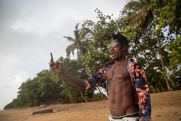 Un jeune vacancier regarde la mer et prend un selfie sur la plage au bord de la mer