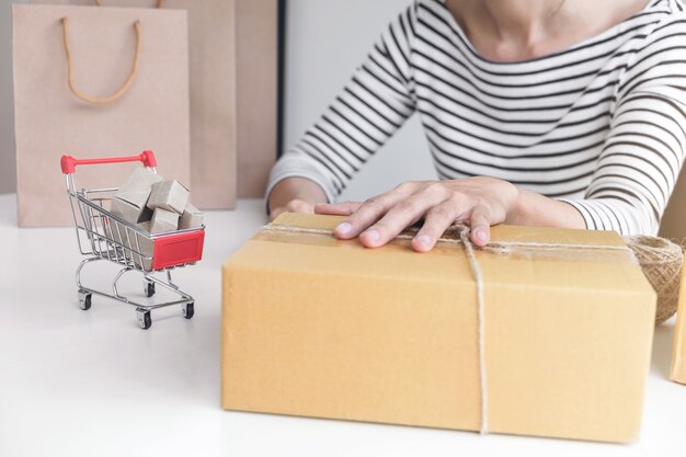 Jeune vendeur femme préparant le paquet à être envoyé Mail transport pour client convenien