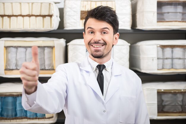 Le jeune vendeur montre des matelas de qualité.