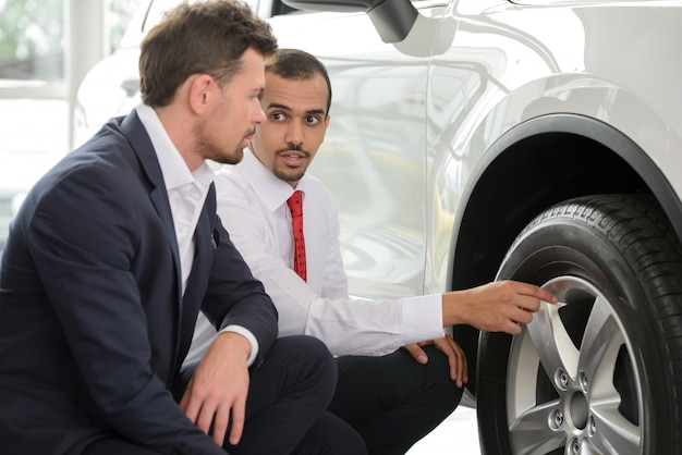 Jeune vendeur de voitures montrant les avantages de la voiture.