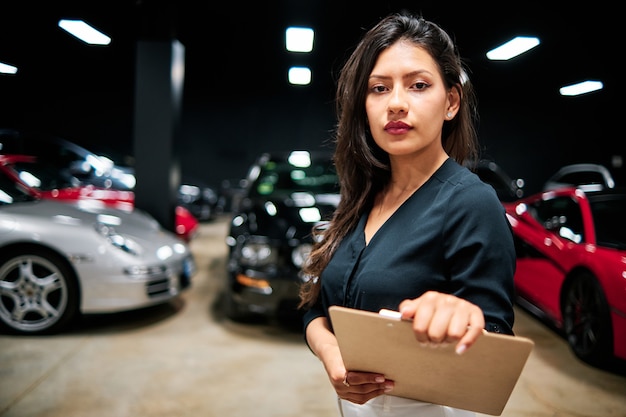 jeune vendeuse latine vendant des voitures de luxe