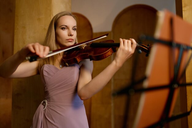 Jeune violoniste solitaire jouant du violon au studio. Portrait en pied d'un musicien