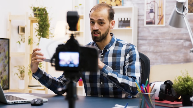 Jeune vlogger enthousiaste faisant une critique d'un produit à l'intérieur d'une boîte blanche. Créateur de contenu créatif.