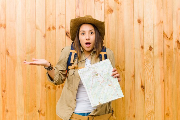 Photo jeune voyageur avec une carte contre le mur en bois