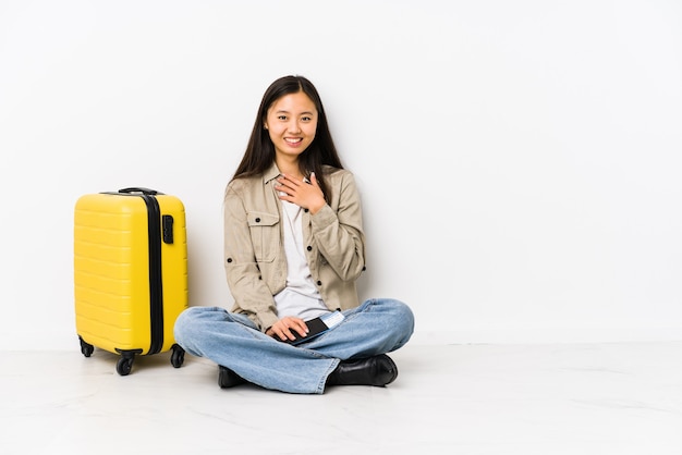 Jeune voyageur chinois femme assise tenant une carte d'embarquement éclate de rire en gardant la main sur la poitrine