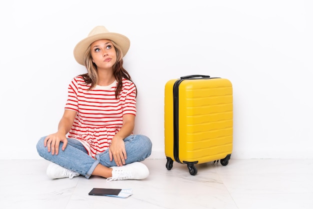 Jeune voyageur fille assise sur le sol isolé sur fond blanc et levant les yeux