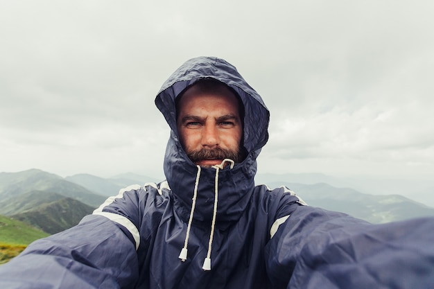 Jeune voyageur prend un selfie sur une chaîne de montagnes