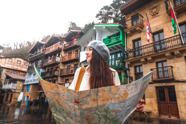 Jeune voyageuse caucasienne regardant une carte et des façades colorées derrière