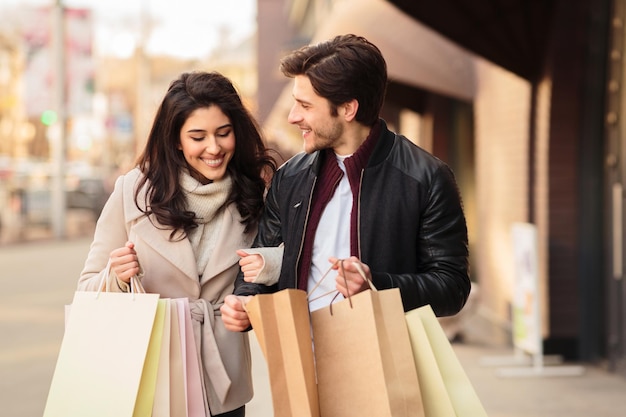 Jeunes accros du shopping à la recherche de sacs à provisions à l'extérieur