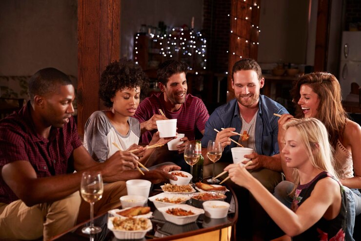 Photo des jeunes adultes mangeant des plats chinois à emporter lors d'une fête à la maison