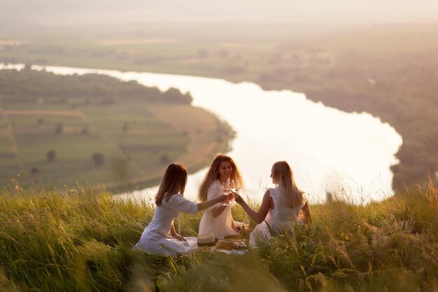 Photo de jeunes amies en train de faire un pique-nique sur la colline au coucher du soleil.