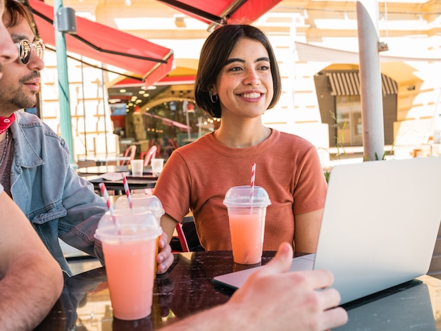 Jeunes amis à l'aide d'un ordinateur portable au café.