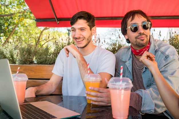 Jeunes amis à l'aide d'un ordinateur portable au café.