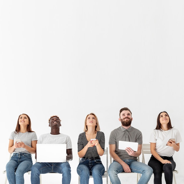 Photo jeunes amis sur des chaises avec des appareils modernes