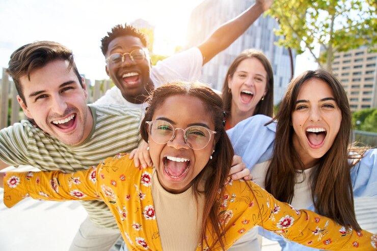 Photo de jeunes amis heureux regardant la caméra et riant un groupe de personnes souriantes s'amusant ensemble à l'extérieur