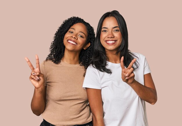 De jeunes amis latins dans le studio montrent le signe de la victoire et sourient largement