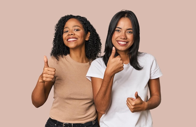 De jeunes amis latins en studio soulevant les deux pouces souriants et confiants