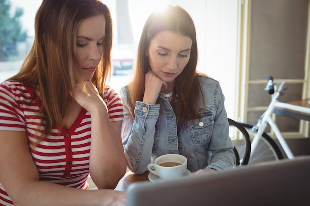 Jeunes amis avec ordinateur portable au café