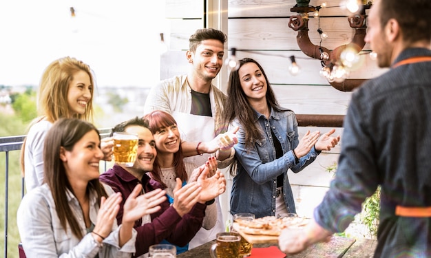 Jeunes amis s'amusant à boire de la bière sur le balcon au dîner de la maison