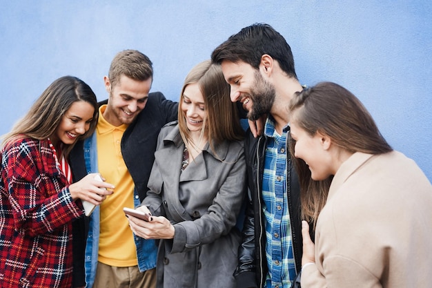 Jeunes amis s'amusant en utilisant des téléphones mobiles en plein air. Se concentrer sur le visage du bon gars