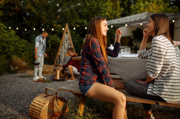 Les jeunes amis se détendent en pique-nique au camping dans la forêt. Jeunes ayant une aventure estivale en VR, camping-car Deux loisirs en couple, voyageant avec remorque