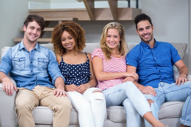 Jeunes amis souriant assis sur un canapé