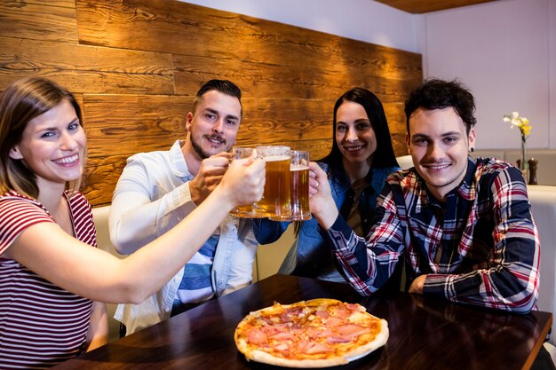 Jeunes amis souriant tout en grillant de la bière