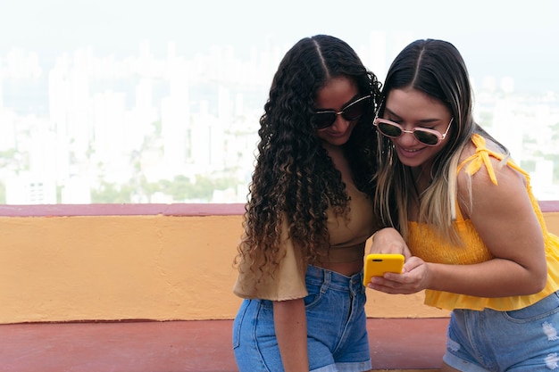 Photo jeunes amis utilisant leur smartphone à l'extérieur