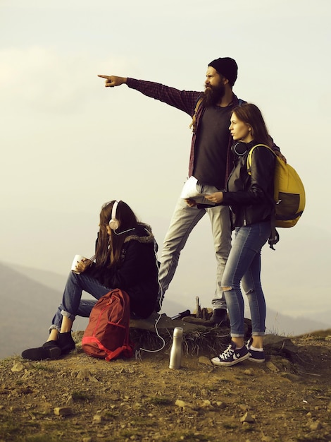 Jeunes amis voyageurs barbu hipster et deux jolies filles femmes avec carte explorent l'itinéraire en plein air...