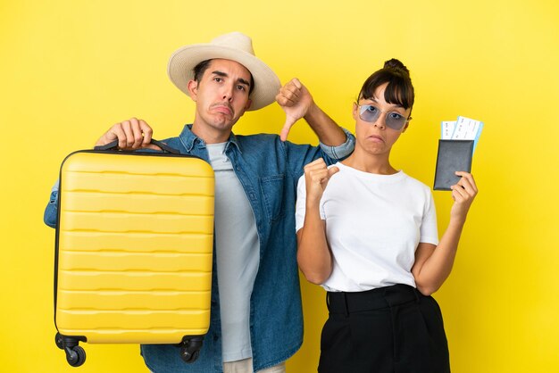 Jeunes amis voyageurs tenant une valise et un passeport isolés sur fond jaune fiers et satisfaits de l'amour de vous-même concept