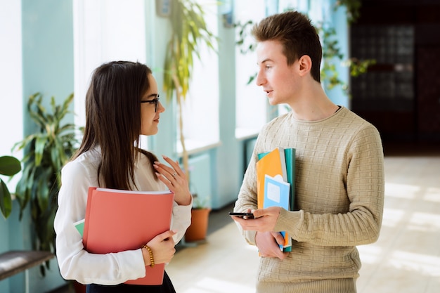 Jeunes apprenants debout dans le couloir de l'école parlant et s'amusant ensemble