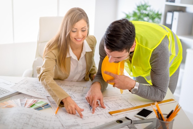 De jeunes architectes qui réussissent discutent des plans de construction et planifient ce qu'il faut changer pour être meilleurs. Ils sont au bureau.