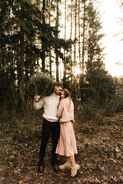 Jeunes beaux amoureux heureux homme et femme histoire d'amour en hiver avec un sapin de Noël vivant dans une forêt de pins au soleil