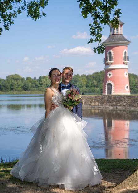 Jeunes et beaux mariés se tiennent sur fond de phare rose Nouveaux mariés sur un wa