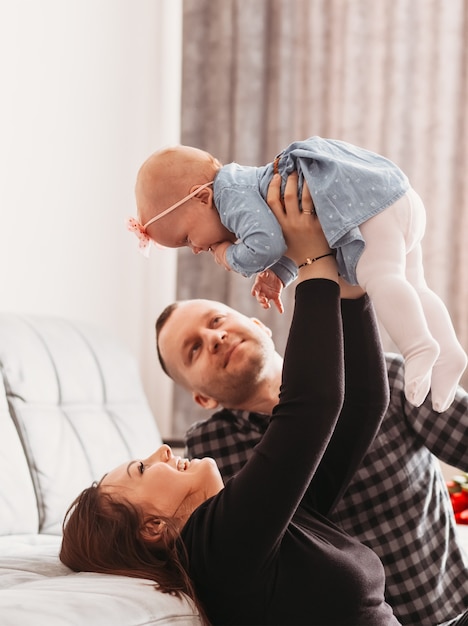 De jeunes beaux parents jouent avec leur bébé fille dans la chambre. Famille heureuse