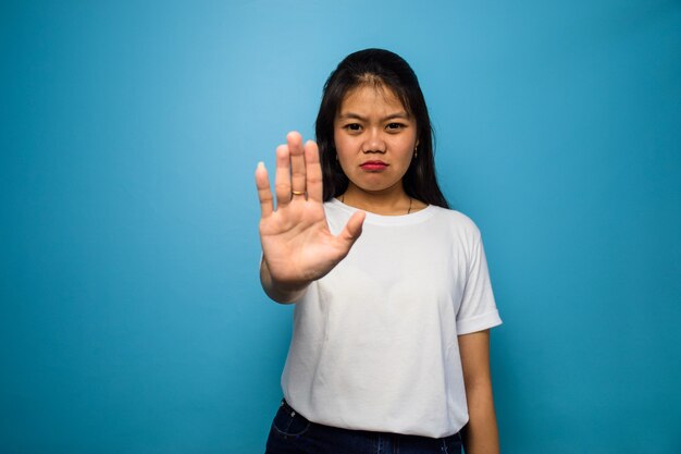 Jeunes belles femmes asiatiques utilisant un t-shirt blanc avec un geste de rejet de fond isolé bleu