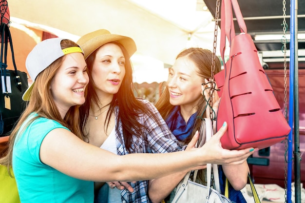 Photo jeunes belles femmes copines au marché aux puces à la recherche de sacs de mode meilleures amies s'amusant et faisant du shopping dans la vieille ville tons de couleurs vives avec halo de soleil amélioré