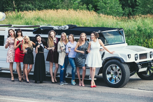 Jeunes belles femmes heureuses célèbrent l'enterrement de vie de garçon dans une limousine décapotable