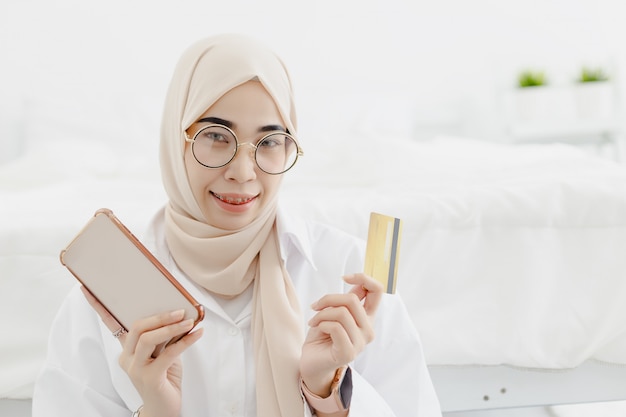 Jeunes belles femmes musulmanes portant le hijab avec sourire joyeux tenant la carte de crédit smartphone, concept de magasinage en ligne.