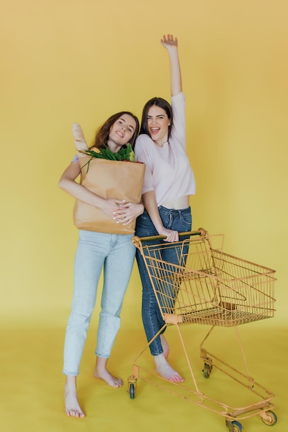 Jeunes belles femmes tenant un sac en papier à emporter de la livraison sur fond jaune