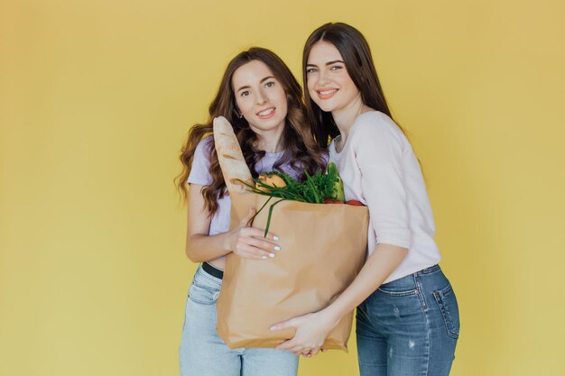 Jeunes belles femmes tenant un sac en papier à emporter de la livraison sur fond jaune