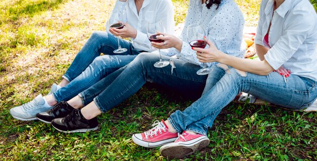 Jeunes belles filles avec verre de vin rouge dans le parc