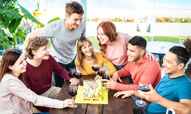 Jeunes branchés s'amusant ensemble en buvant du vin au penthouse sur le jardin privé