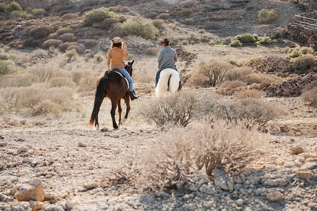 Les jeunes à cheval faisant une excursion au coucher du soleil se concentrent sur le dos de la femme