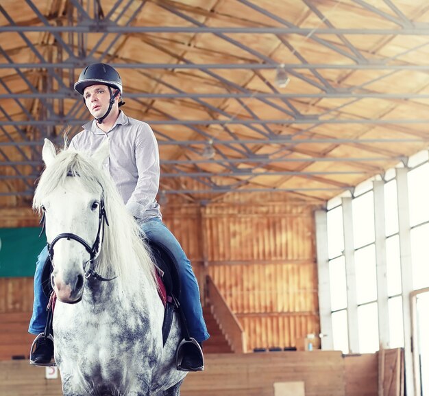 Jeunes sur un cheval s'entraînant dans une arène en bois